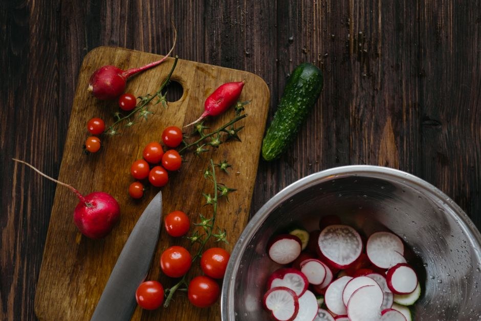 Fresh vegetables arranged on a wooden kitchen surface.